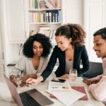 a team of three around a laptop working at a table
